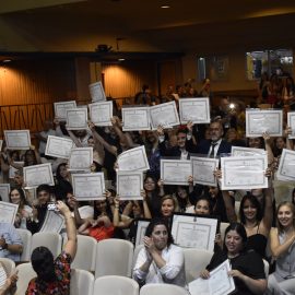 Egresades mostrando sus títulos.